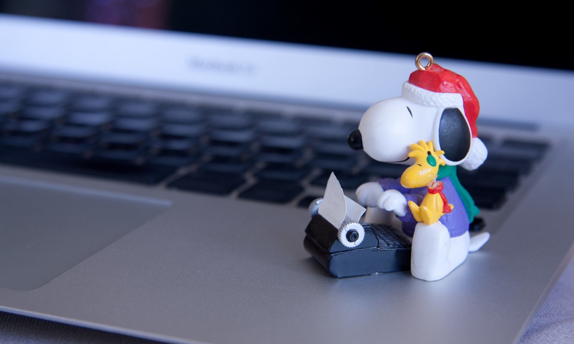 Cartoon character with old typewriter sitting next to keyboard of a laptop.